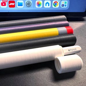 Puede incluir: Una colección de estuches coloridos para Apple Pencil y un Apple Pencil. Los estuches son de varios colores, incluyendo negro, amarillo, morado y gris. Un estuche blanco está abierto, revelando el Apple Pencil con la palabra "Pencil".