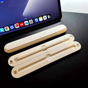 May include: A white case with a textured surface holds a white Apple Pencil. The case has a magnetic closure and folds in half for compact storage.