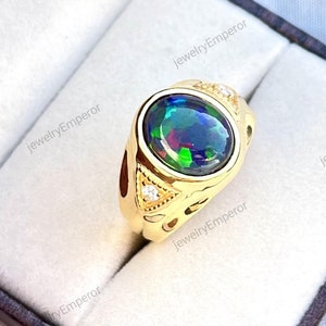 May include: A gold ring with a large oval-shaped black opal gemstone surrounded by smaller white gemstones. The ring is in a velvet box.