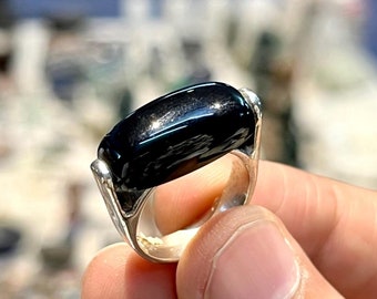 May include: A black gemstone ring with a silver band. The ring is set with a rectangular black stone.