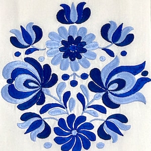 May include: Blue and white embroidered floral design on a white fabric background. The design features stylized flowers and leaves.