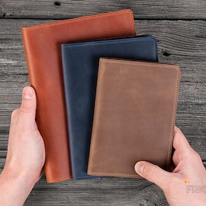 May include: Three leather-bound journals in different sizes. The largest journal is brown, the middle journal is blue, and the smallest journal is brown.