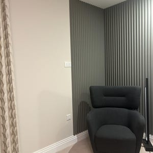 Puede incluir: Un sill&oacute;n negro con respaldo alto y patas de madera se encuentra en una habitaci&oacute;n con una pared texturizada gris y una alfombra beige.