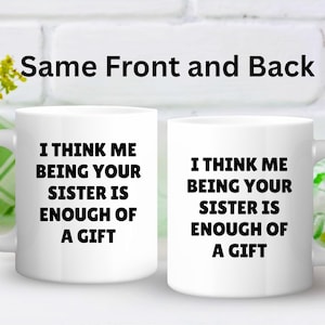 May include: Two white ceramic mugs with the text "I THINK ME BEING YOUR SISTER IS ENOUGH OF A GIFT" in black. The phrase "Same Front and Back" is above the mugs. The mugs have a curved handle.