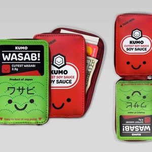 May include: A red and green zippered wallet with a cartoon design. The front of the wallet features a red soy sauce packet with the text "KUMO CUTEST SOY SAUCE SOY SAUCE". The back of the wallet features a green wasabi packet with the text "KUMO WASAB! CUTEST WASABI 2.5g Product of Japan ワサビ Easy to tear at any point".