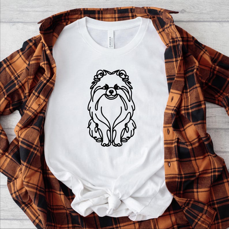May include: White t-shirt with a black line drawing of a Pomeranian dog on the front.
