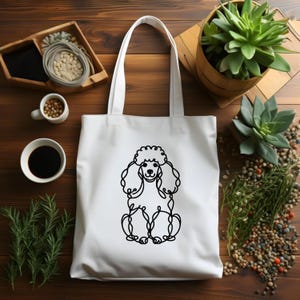 May include: White canvas tote bag with a black line drawing of a poodle on the front.