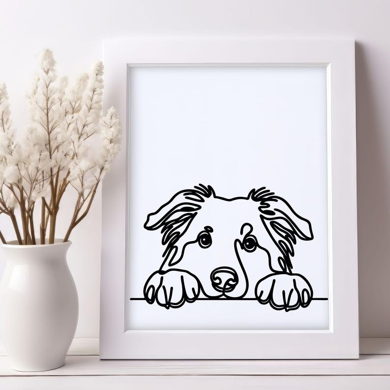 Puede incluir: Una impresi&oacute;n enmarcada en blanco y negro de un rostro de perro. El perro est&aacute; dibujado con una l&iacute;nea continua, con sus patas apoyadas en una l&iacute;nea horizontal. La obra de arte se muestra en un marco blanco.