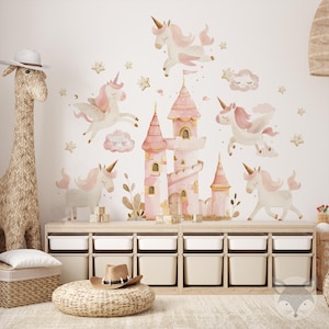 May include: Pink and white unicorn wall decals with a pink castle and clouds. The decals are on a white wall above a set of wooden storage bins.