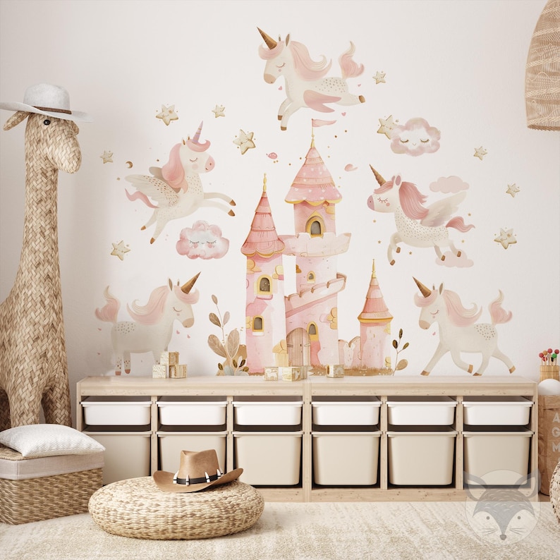 May include: Pink and white unicorn wall decals with a pink castle and clouds. The decals are on a white wall above a set of wooden storage bins.