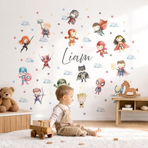Peut inclure: Un ensemble d'autocollants muraux représentant des illustrations à l'aquarelle de divers super-héros, dont Iron Man, Batman, Spider-Man et d'autres, entourant le prénom Liam en écriture noire, agrémenté de petites étoiles et nuages colorés.