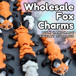 May include: Orange fox charms with black accents and white details are displayed. The charms are 3D printed and have a cartoon-like appearance. Text in the image reads "Wholesale Fox Charms" and "Bulk Handmade Jewelry Supplies."