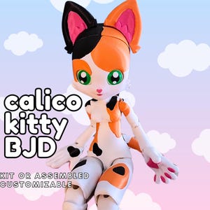 May include: A calico kitty BJD doll with a white, orange, and black color scheme. The doll has large green eyes, pink inner ears, and a pink nose. The text "calico kitty BJD" is displayed on the image, along with "KIT OR ASSEMBLED CUSTOMIZABLE".
