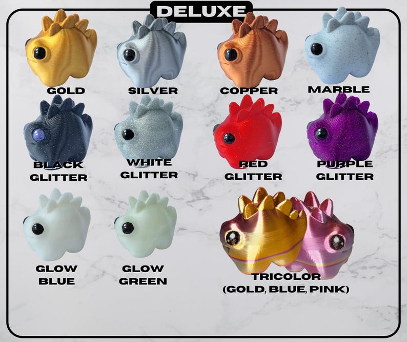 May include: A collection of Deluxe figurines in various colors, including gold, silver, copper, and marble. The figurines have a dinosaur-like design with the text "DELUXE" at the top and color labels like "BLACK GLITTER" and "GLOW BLUE".
