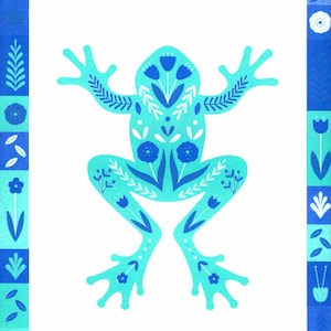 Op de afbeelding: Een lichtblauwe kikkerillustratie gecentreerd op een witte achtergrond, versierd met donkerblauwe bloem- en bladpatronen. Het kunstwerk is ingesloten door een rechthoekige rand met afwisselende vierkanten van blauwe en lichtblauwe botanische motieven.