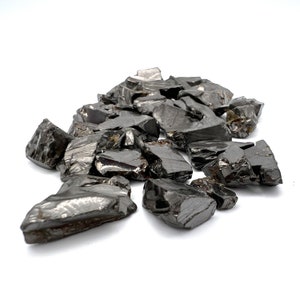 May include: A pile of black obsidian crystal chips. The chips are rough and jagged, with a shiny, almost metallic sheen.