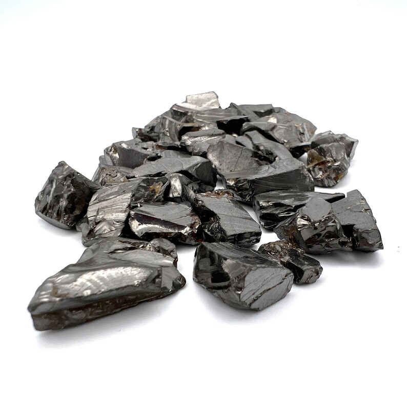 May include: A pile of black obsidian crystal chips. The chips are rough and jagged, with a shiny, almost metallic sheen.