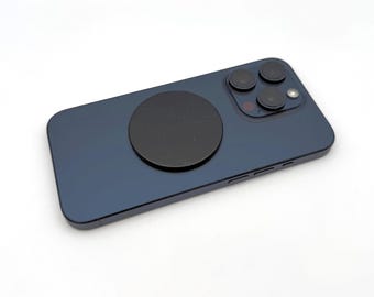 May include: A dark blue smartphone with a black circular phone grip attached to the back. The phone has a triple-lens camera system and a flash. The grip has a marble-like texture.