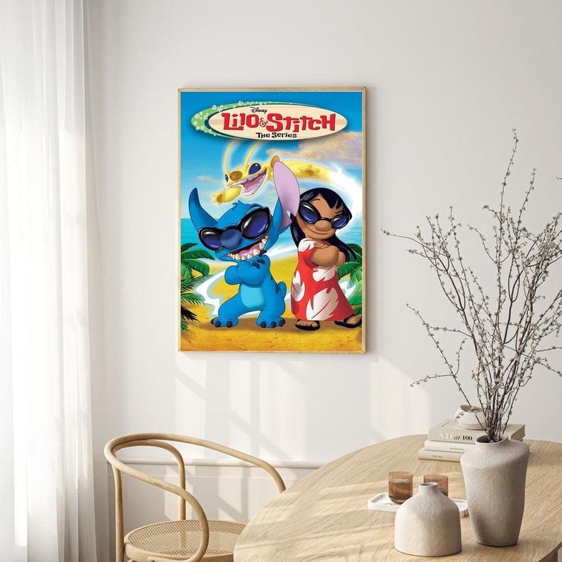 May include: A framed poster featuring the characters Lilo and Stitch from the Disney animated series "Lilo & Stitch: The Series". The poster has a blue background with palm trees and a beach scene. Stitch is wearing sunglasses and a blue shirt, while Lilo is wearing a red dress and sunglasses. The text "Disney Lilo & Stitch The Series" is printed at the top of the poster.