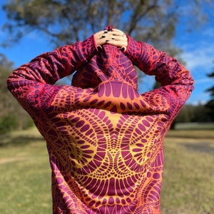 May include: A hooded sweatshirt with a colorful, abstract pattern in shades of orange, yellow, and purple. The pattern is reminiscent of a mandala or other geometric design.