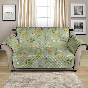 May include: A green floral patterned quilted sofa slipcover with a black trim. The slipcover is designed to protect furniture from spills and stains.