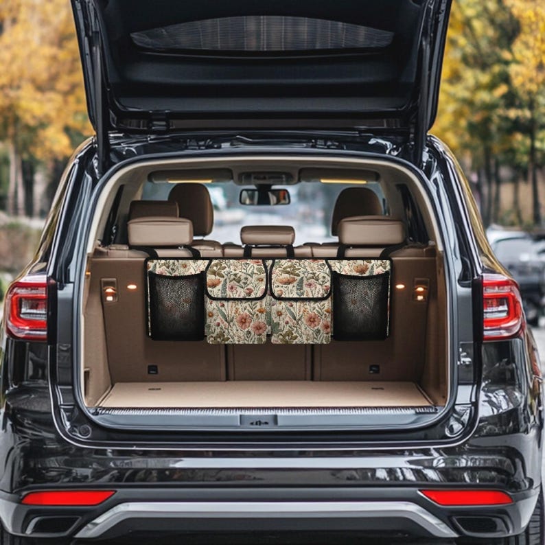 May include: A black car with the back hatch open, revealing a floral patterned car organizer with three compartments. The organizer is hanging from the back headrests.