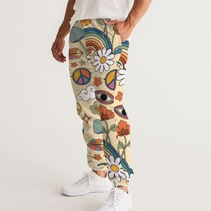 Puede incluir: Un pantal&oacute;n de ch&aacute;ndal de color crema con un estampado retro colorido que incluye s&iacute;mbolos de paz, flores, arco&iacute;ris y ojos.