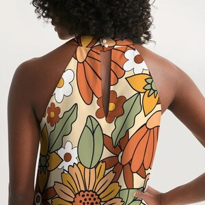 May include: A halter top with a retro floral print in shades of orange, yellow, green, and white. The top has a keyhole back and a sleeveless design.