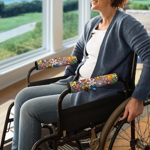 Peut inclure: Des housses d'accoudoirs de fauteuil roulant avec un motif floral coloré dans les tons de rose, jaune, bleu et orange. Les housses sont conçues pour s'adapter aux accoudoirs d'un fauteuil roulant, offrant confort et une touche décorative. Le motif floral ajoute une esthétique joyeuse et vibrante.