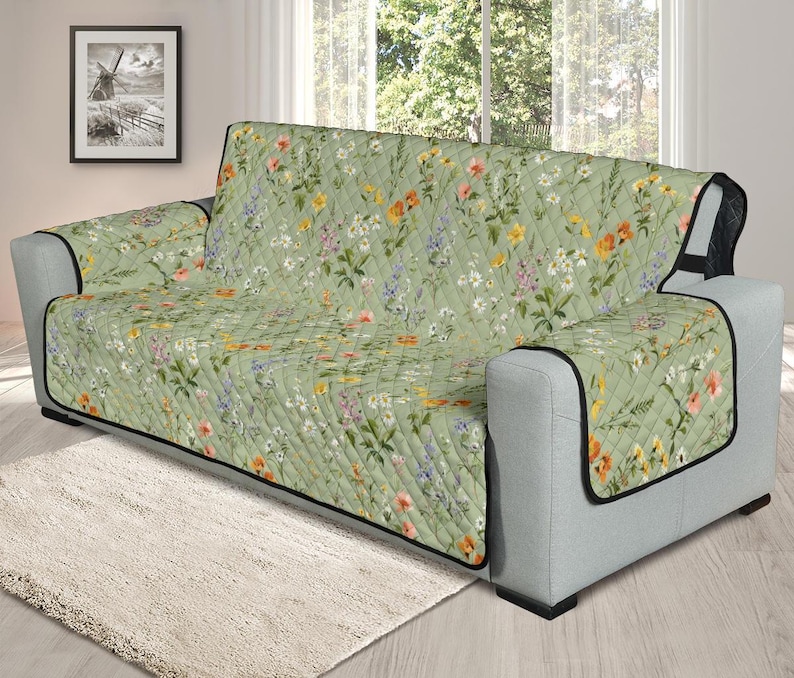 May include: A green floral sofa cover with a quilted pattern. The cover features a variety of flowers in shades of pink, yellow, and white.