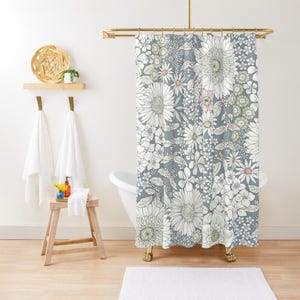 May include: A shower curtain with a floral pattern on a light blue background. The flowers are white with hints of pink and green.