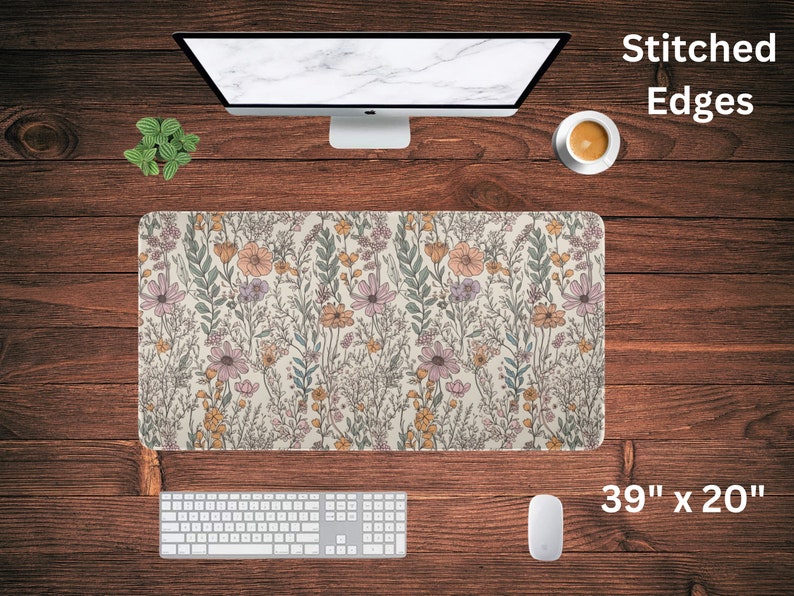 May include: A floral patterned desk mat with stitched edges. The mat is 39 inches by 20 inches and features a light beige background with a variety of pink, yellow, and green flowers.