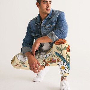 Puede incluir: Una persona que lleva una chaqueta vaquera y pantalones de color crema con un estampado colorido de flores, arco&iacute;ris, estrellas y nubes.