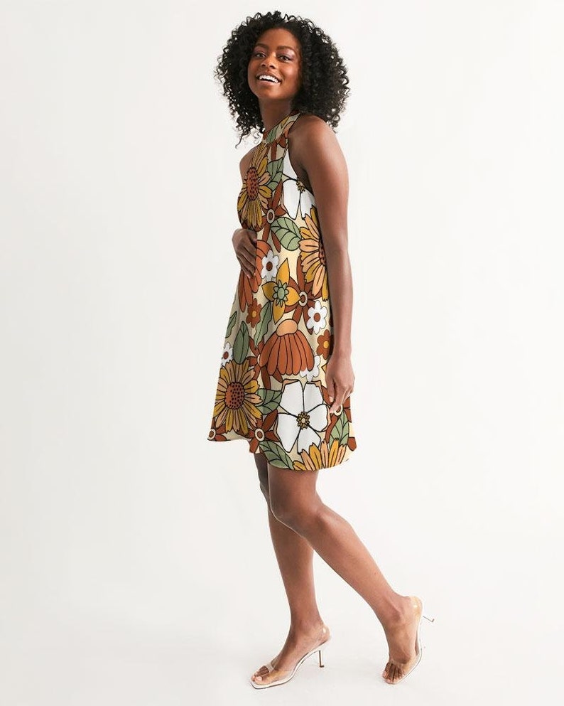 May include: A sleeveless dress with a floral print in shades of orange, brown, white, and green. The dress has a halter neckline and a flowy silhouette.