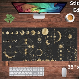 May include: A black and gold mouse mat with a celestial design featuring moons, stars, and geometric patterns. The mouse mat has stitched edges and measures 35 inches by 16 inches.