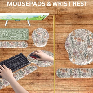 May include: A set of floral patterned mousepads and wrist rests. The mousepads are round and the wrist rests are rectangular. The wrist rests have a floral pattern with pink, white, and green flowers. The mousepads have a similar floral pattern with pink, white, and green flowers.