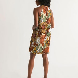 May include: A halter dress with a retro floral print in shades of orange, brown, green, and white on a cream background.