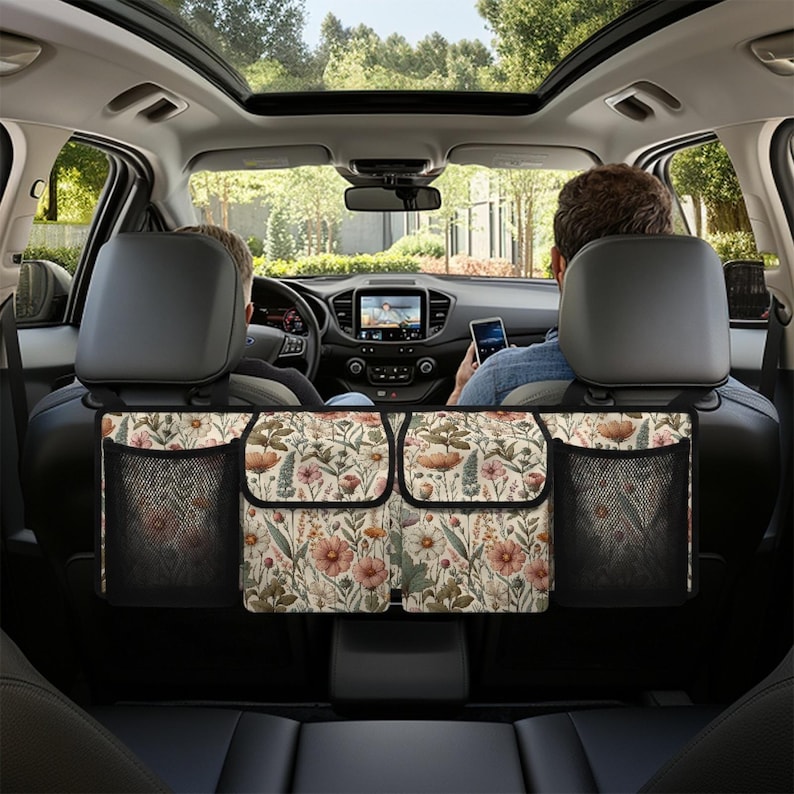 May include: A car backseat organizer with a floral print and three mesh pockets. The organizer hangs from the headrests and has a beige background with pink, orange, and green flowers.