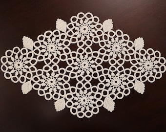 Könnte beinhalten: Weiße Häkeldeckchen in Diamantform mit filigranen Blumendesigns.