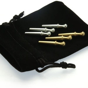 Op de afbeelding: Een zwarte fluwelen zak met een trekkoord, die zes gitaarstemknoppen bevat. Drie van de stemknoppen zijn zilver en drie zijn goud.