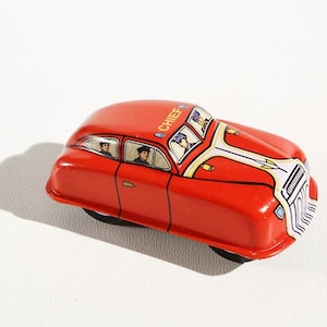 Könnte beinhalten: Rotes Spielzeugauto mit einem weißen Streifen und dem Wort "CHIEF" auf dem Dach. Das Auto hat vier Räder und ist aus Metall. Es befinden sich vier Personen im Auto.