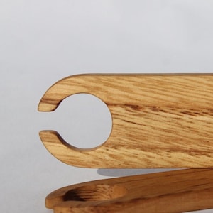 May include: A wooden loom shuttle with two rounded ends and a smooth, light brown finish.