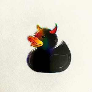 May include: A black rubber duck with red horns and a rainbow iridescent finish. The duck has a yellow beak and black eyes.