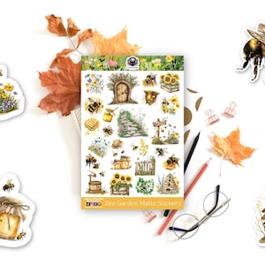 May include: A selection of matte stickers with bee-themed illustrations. The sheet features various designs, including bees, honey pots, beehives, and floral elements. Additional stickers show a bee garden sign and a bee with a honey dipper. The stickers are surrounded by autumn leaves.