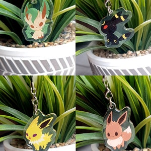 May include: Four different Pokemon character charms, each with a different color scheme and design. The charms are made of clear acrylic and feature a silver chain.