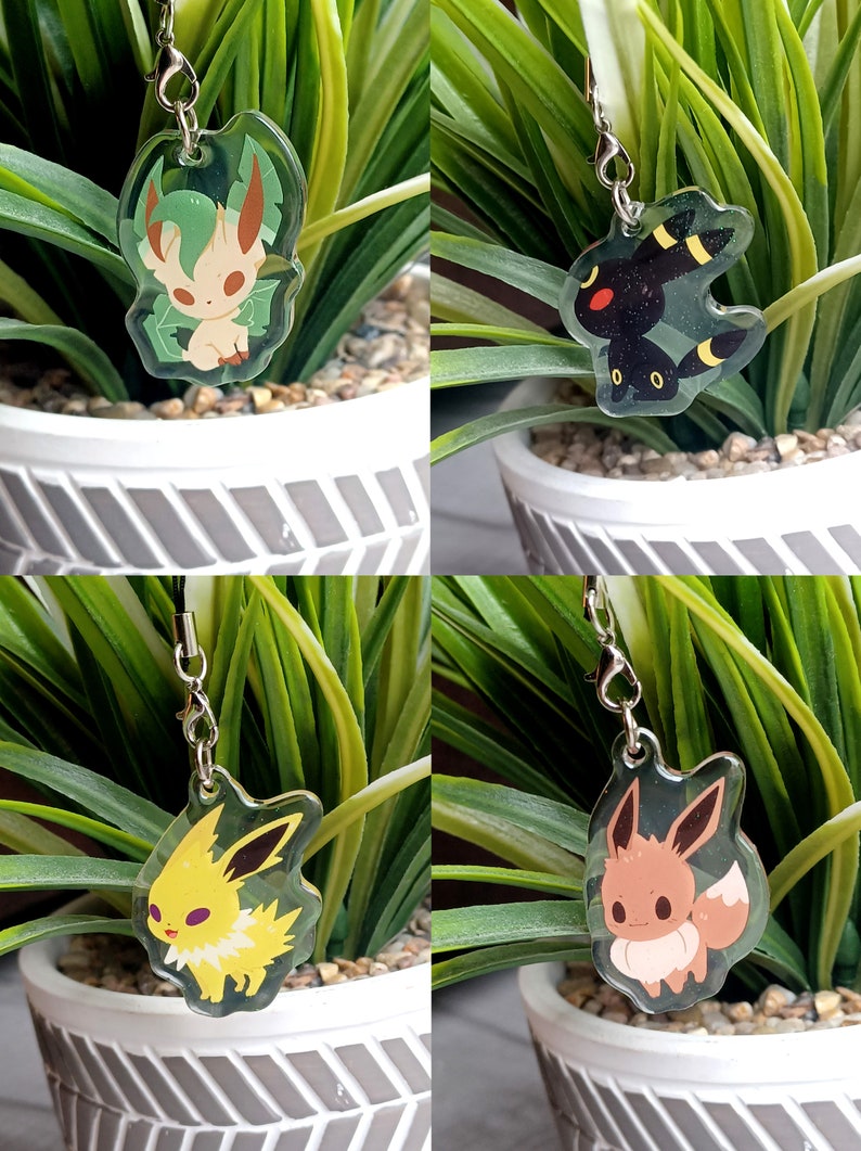 May include: Four different Pokemon character charms, each with a different color scheme and design. The charms are made of clear acrylic and feature a silver chain.