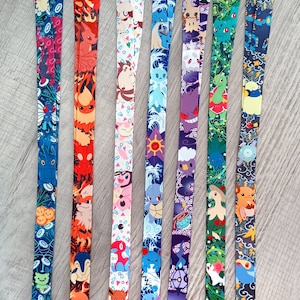 May include: Set of seven colorful lanyards featuring different Pokemon characters. Each lanyard has a unique design with a variety of colors and patterns. The lanyards are approximately 18 inches long and have a metal clip at the end.