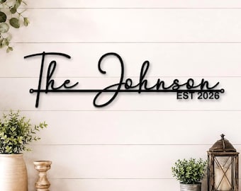 May include: A black metal wall sign featuring the text The Johnson in a cursive script font. A horizontal line runs through the centre of the text, and the words EST 2026 are printed in a bold, sans-serif font below the line on the right side.