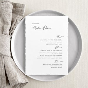 May include: A wedding menu with a rustic, hand-written font. The menu features a welcome message, "Welcome, Raghav Ober", followed by the courses: First, Main, and Dessert. The first course is a Mesclun Greens Salad with Grilled Peaches, Herbed Focaccia, Cucumber Herb Vinaigrette, Watermelon Mojito Bites with Feta Cheese, Mint, Mosto Glaze. The main course is a Bordelaise Short Rib and Shrimp Duo, Sweet Potato Puree, Seared Brussels Sprouts, Red Wine Demi Sauce, Ricotta Risotto with Wild Mushrooms, Porcini Broth, Arborio Rice, Sauteed Mushrooms, Brunoise Tomatoes, Shaved Parmesan, Fried Cremini. The dessert is White Chocolate and Raspberry Cake, Coffee and Tea Service, After Dinner Liqueurs.