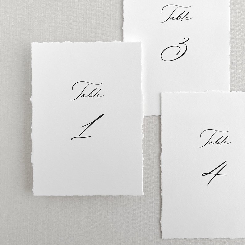 Pu&ograve; includere: Tre carte bianche con calligrafia nera che recita "Tavolo 1", "Tavolo 3" e "Tavolo 4".